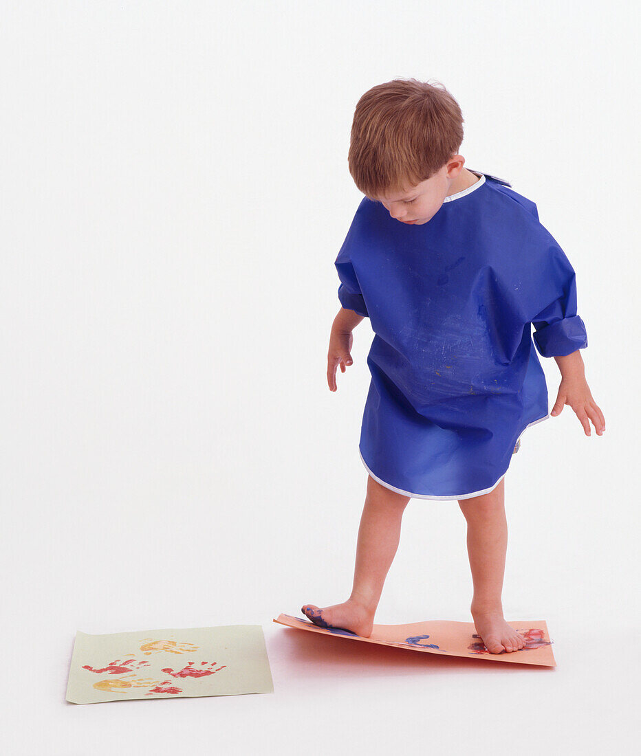 Barefoot toddler making footprints with paint on paper