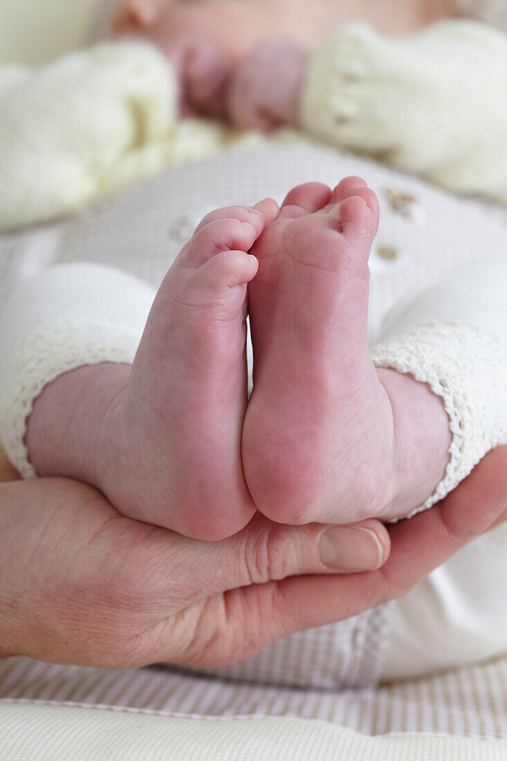 Bare soles of feet of baby girl cradled in cupped hand