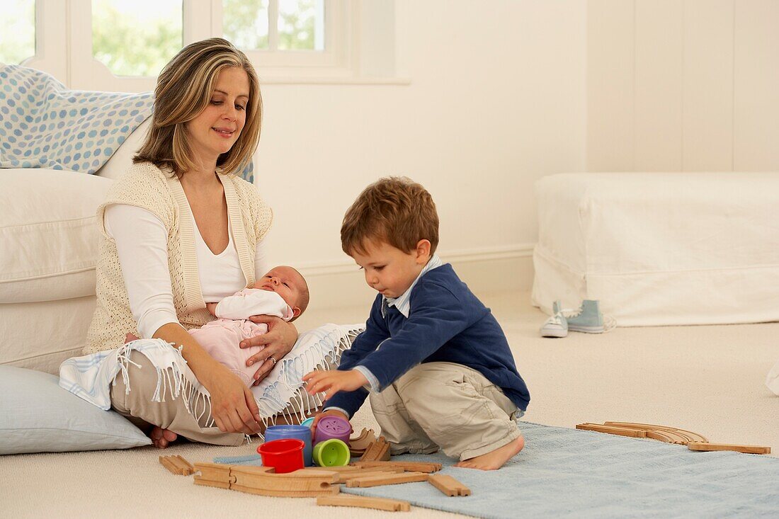 Mother holding baby on her lap as she plays with young son