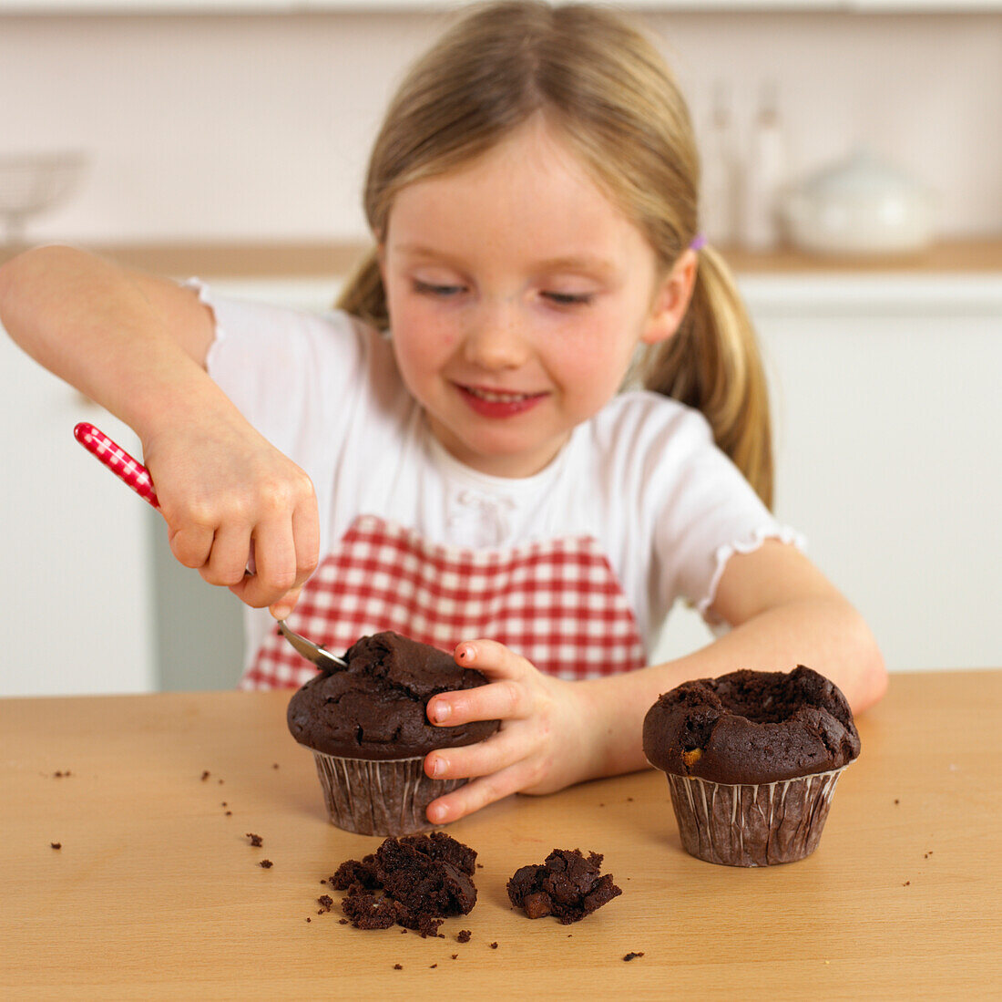 Girl pushing spoon into chocolate muffin