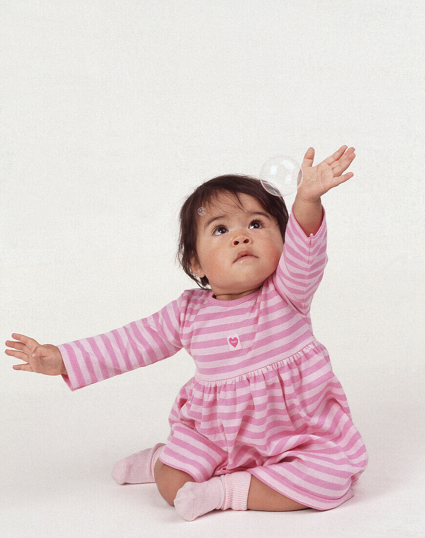 Small girl sitting down with her arms in the air