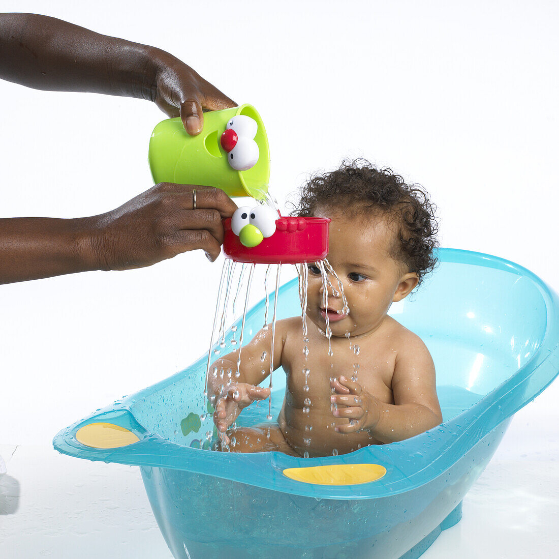 Hand pouring water through a toy for a baby in a bath