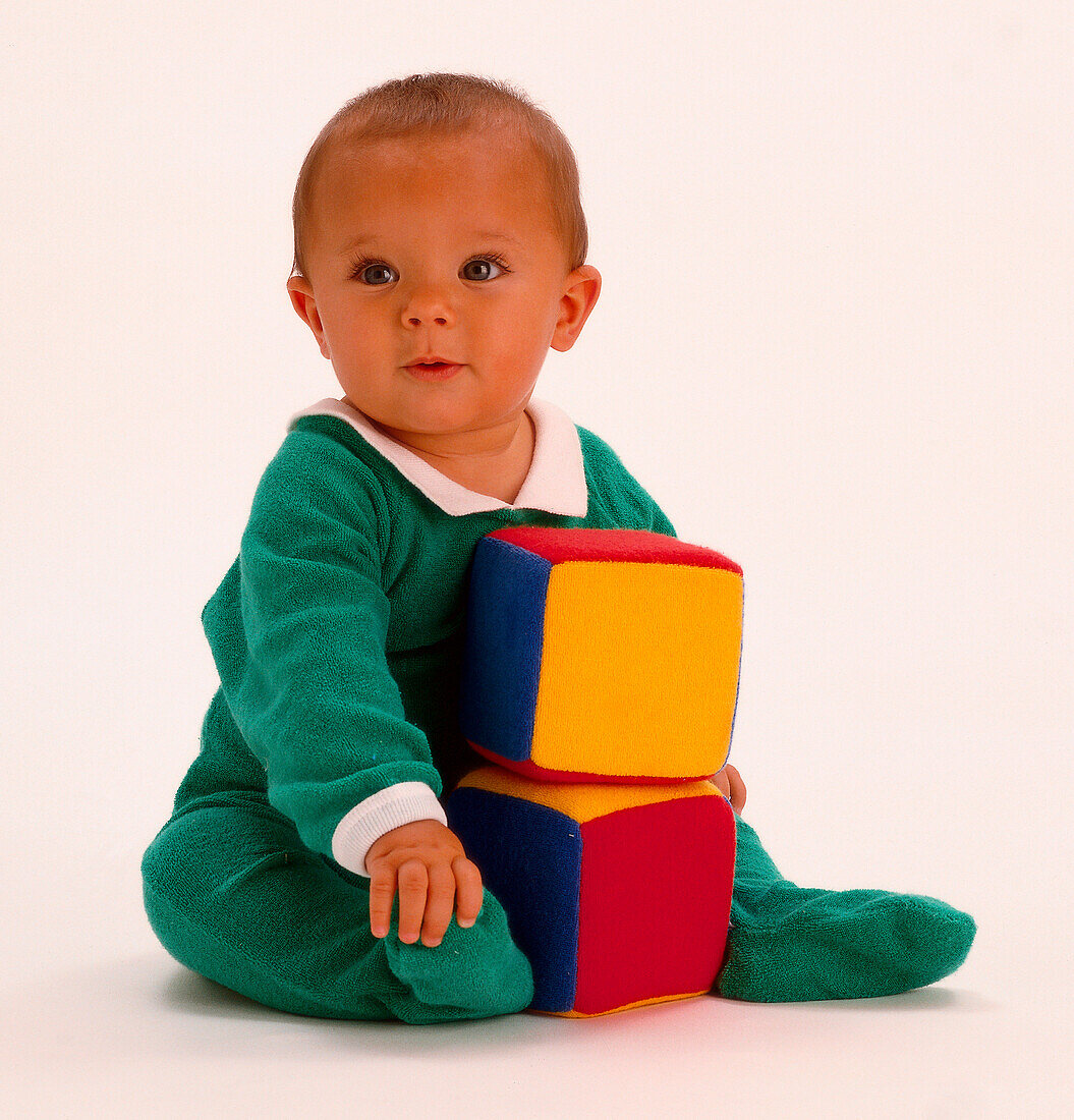 Baby seated with two fabric multi-coloured cubes