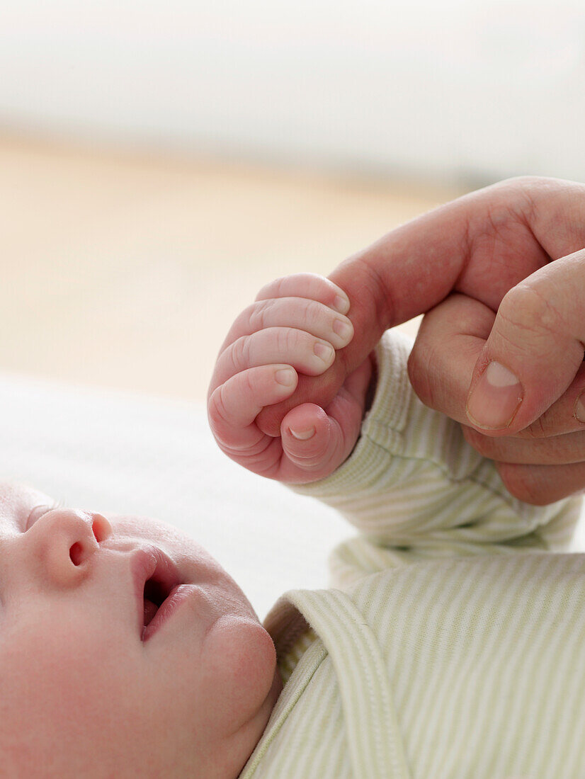 Baby's hand around a woman's finger