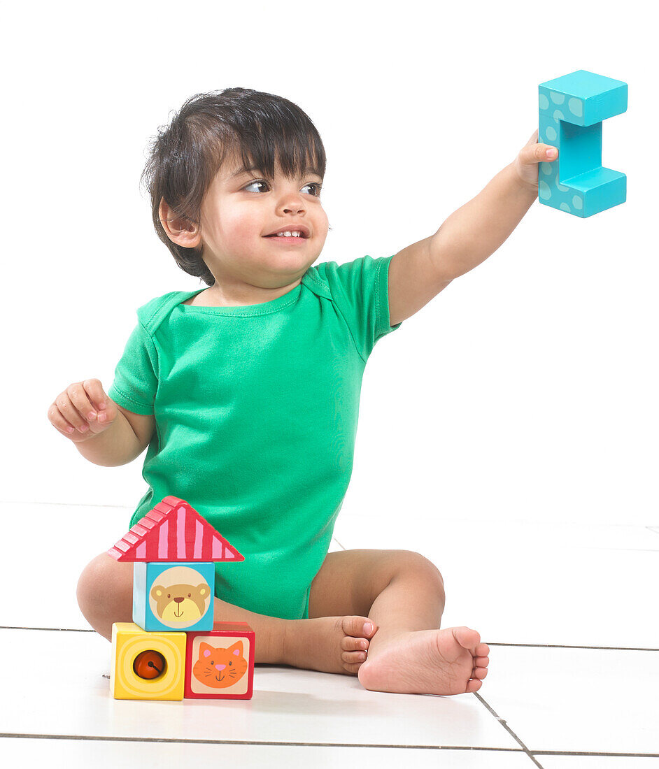 Baby boy sitting playing with building blocks