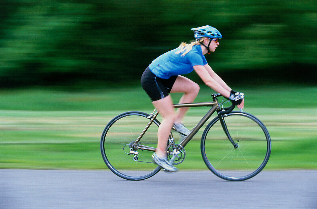 Young woman riding racing bicycle at speed on country road