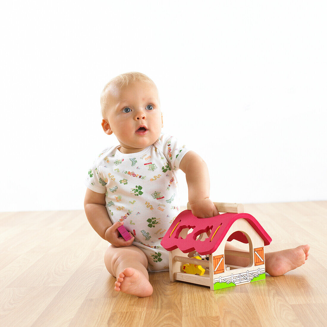 Baby girl sitting on floor playing with farmhouse toy