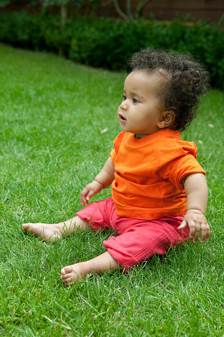 Baby girl sitting on lawn in garden