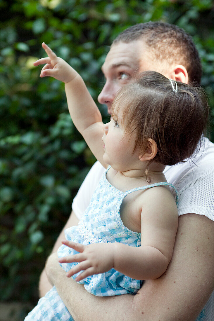 Man holding baby girl who is pointing her finger