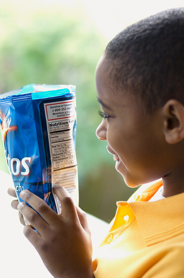 Boy reading ingredients on the back of savoury snacks