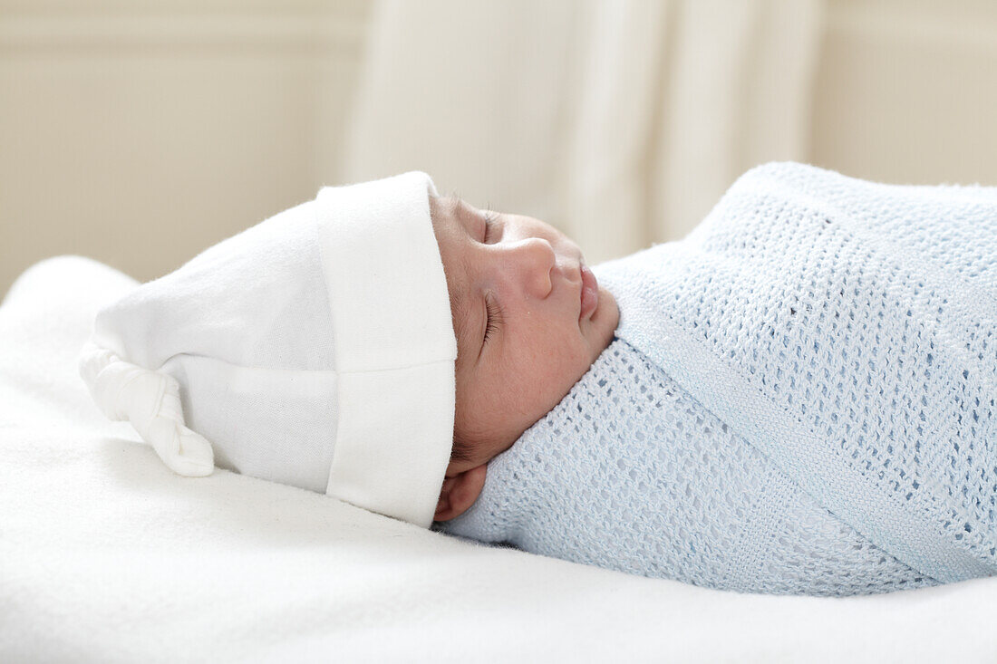 Sleeping baby boy wrapped in blanket wearing hat