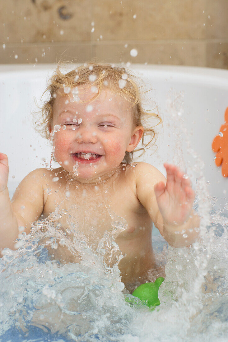 Girl playing in a bath splashing