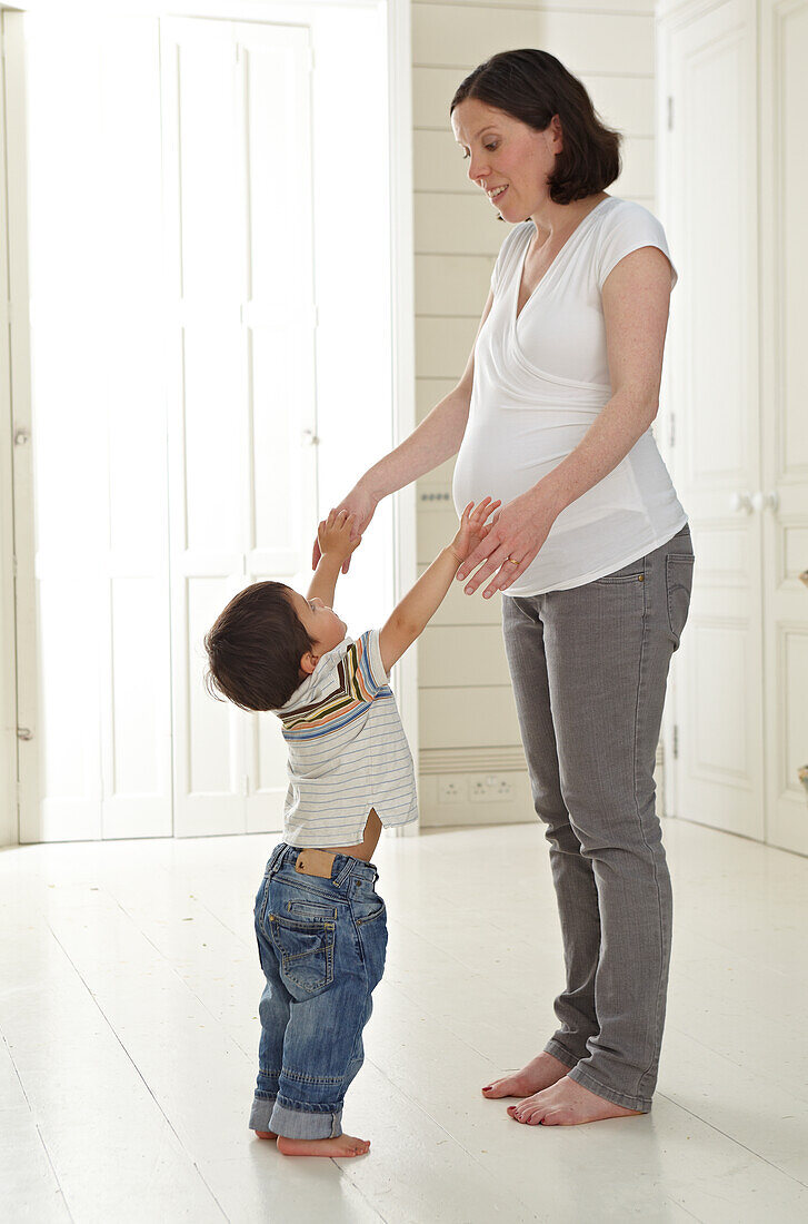 Pregnant woman standing holding hands with small boy
