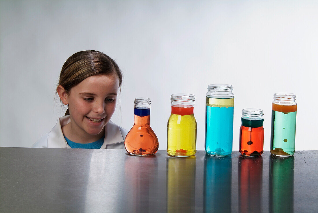 Girl looking at bottles containing coloured liquids