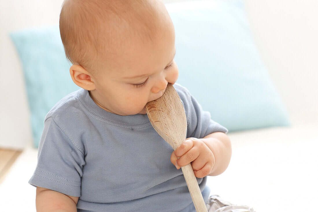 Baby boy chewing wooden spoon
