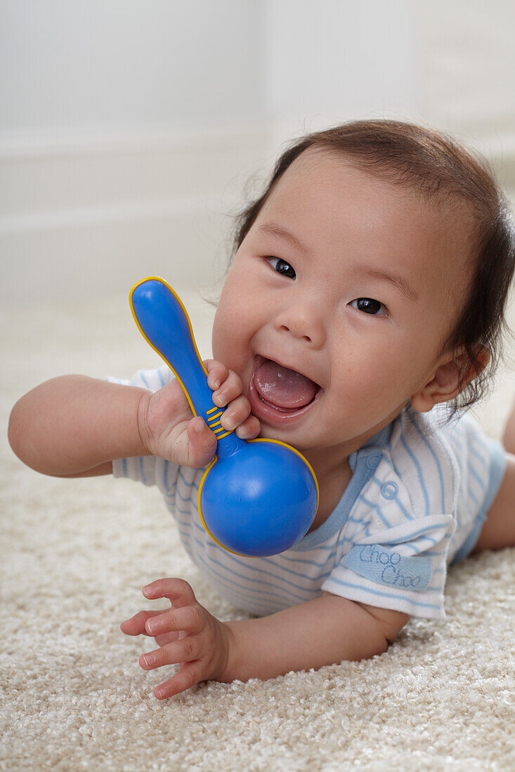 Baby boy holding plastic rattle