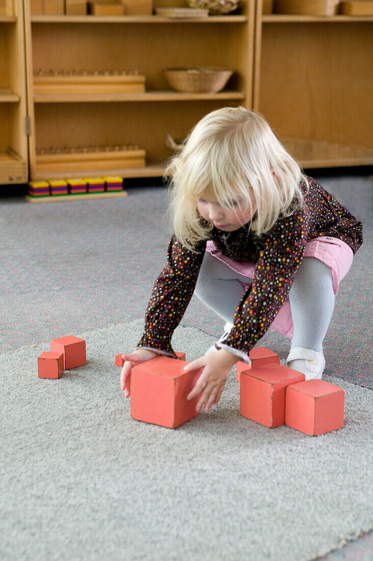 Girl picking up red wooden block