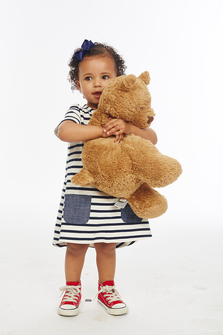 Little girl in stripey dress playing with bear
