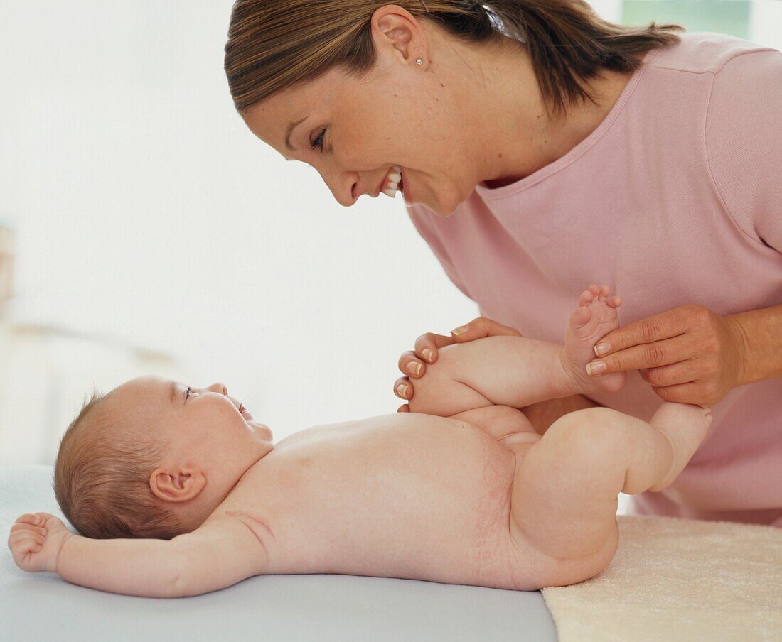 Woman smiling down at baby lying on her back