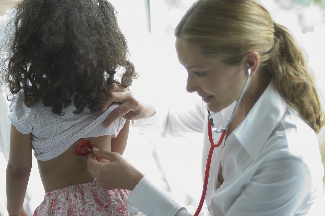 Doctor holding stethoscope on girl's back