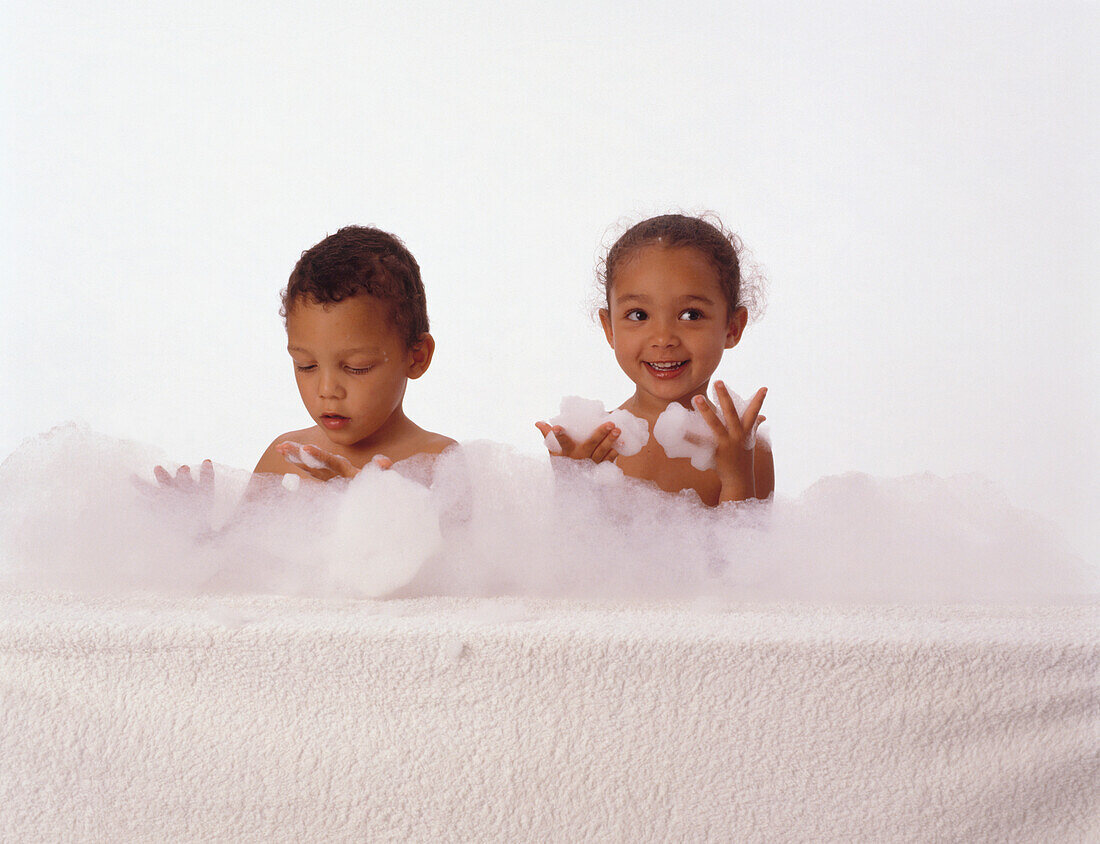 Girl and boy in bubble bath with bubbles on hands