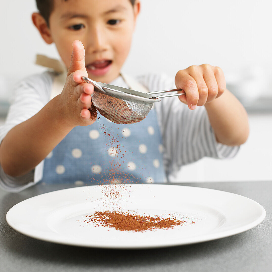 Boy sifting chocolate powder onto a plate