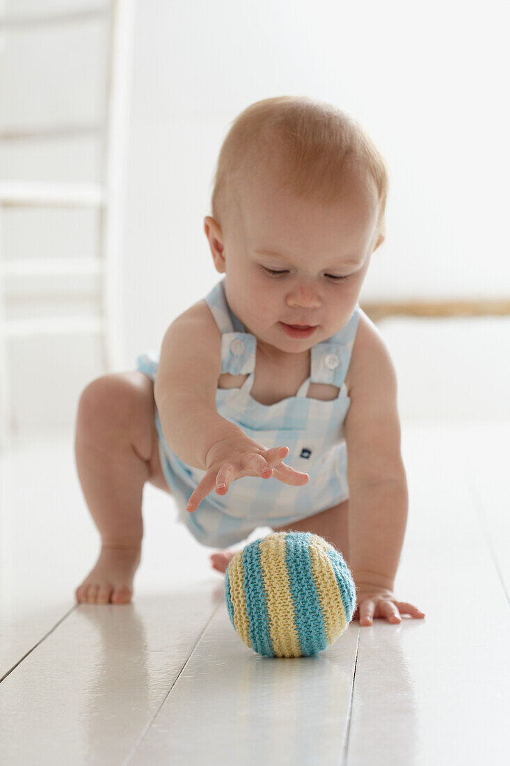 Baby girl playing with knitted soft toy ball