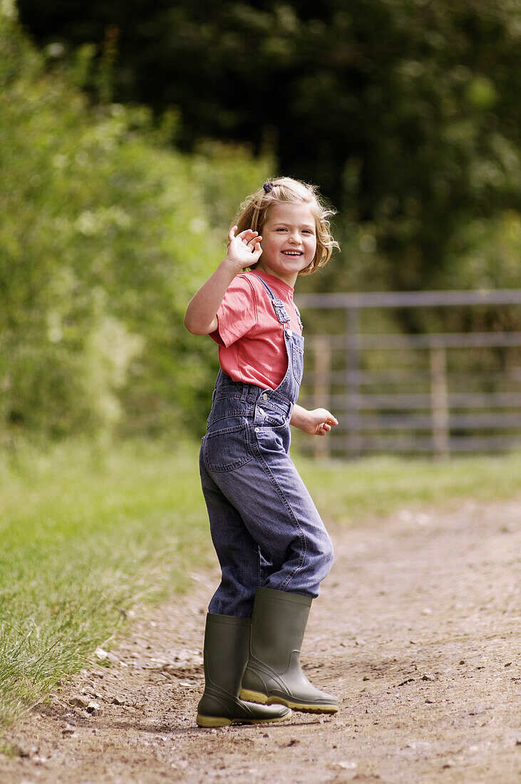 Girl in dungarees turning round and waving