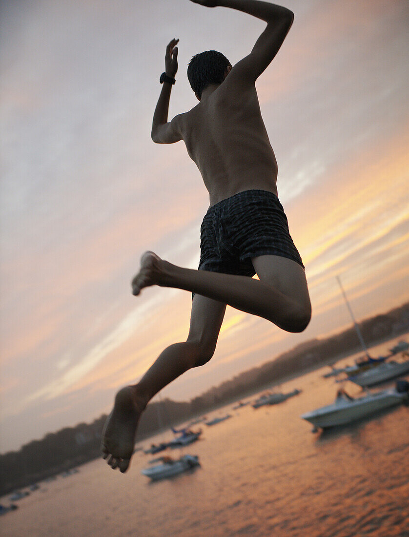 A boy leaping off a dock