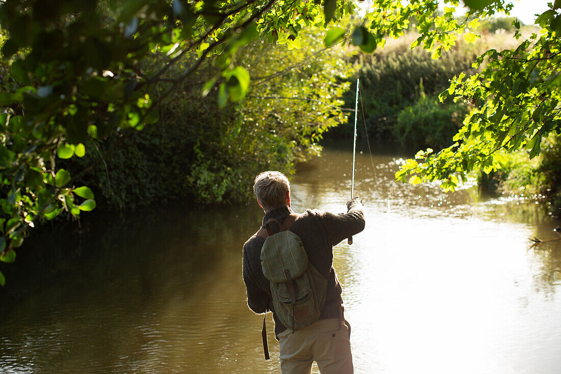 Man casting fly fishing line into a river