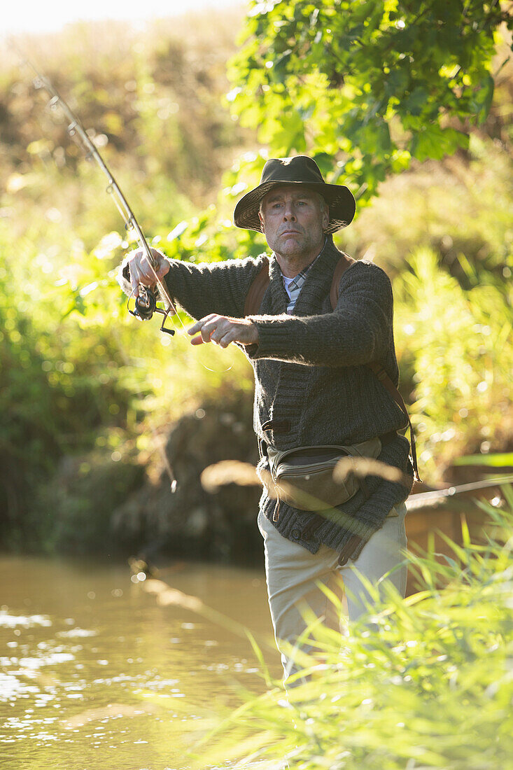 Man casting fly fishing pole at a river