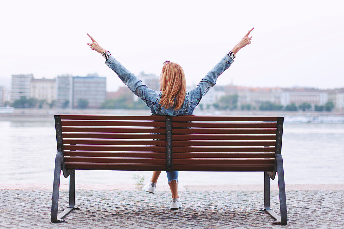 Woman with arms raised on bench