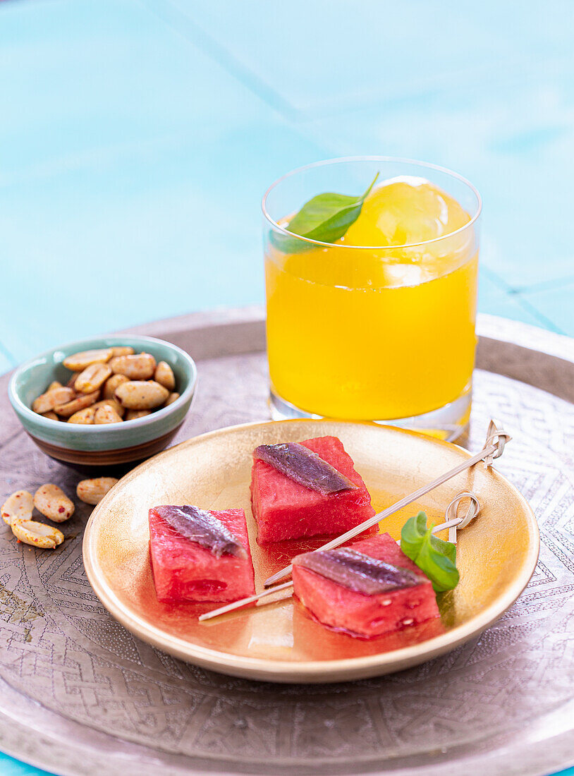 Watermelon bites with anchovy fillets and an orange fizz highball