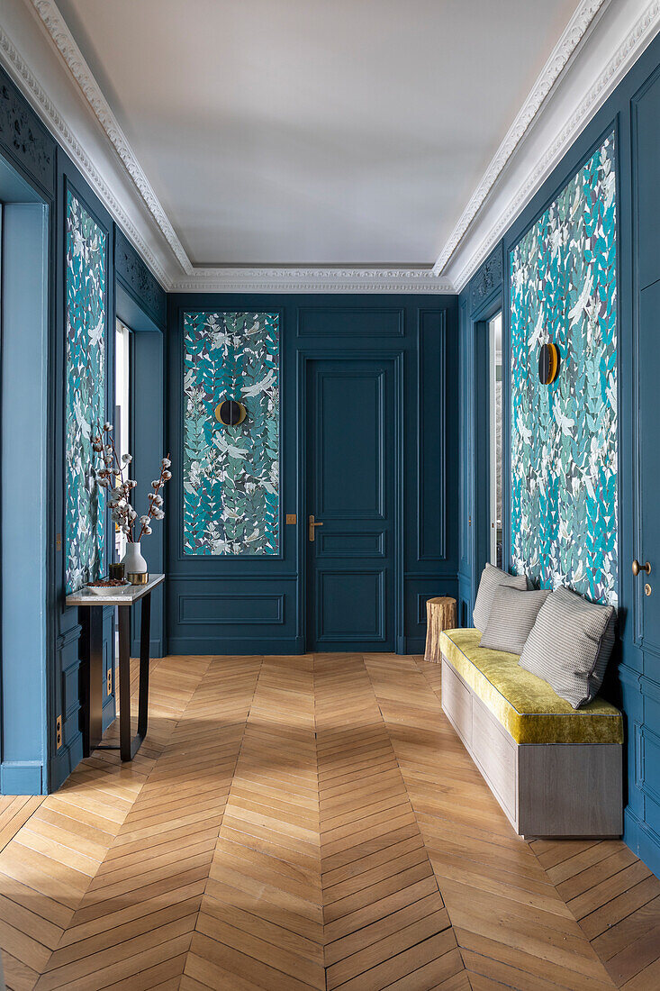 Hallway in blue tones with herringbone parquet flooring and wallpaper with floral motifs