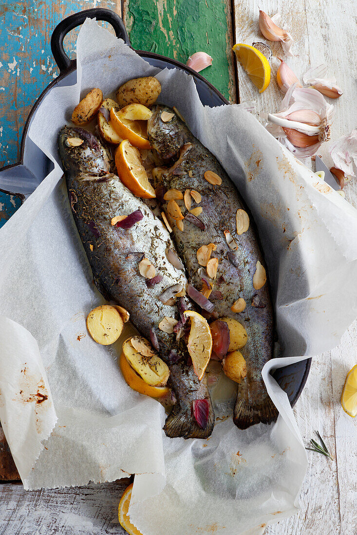 Baked trout with pieces of potatoes and garlic