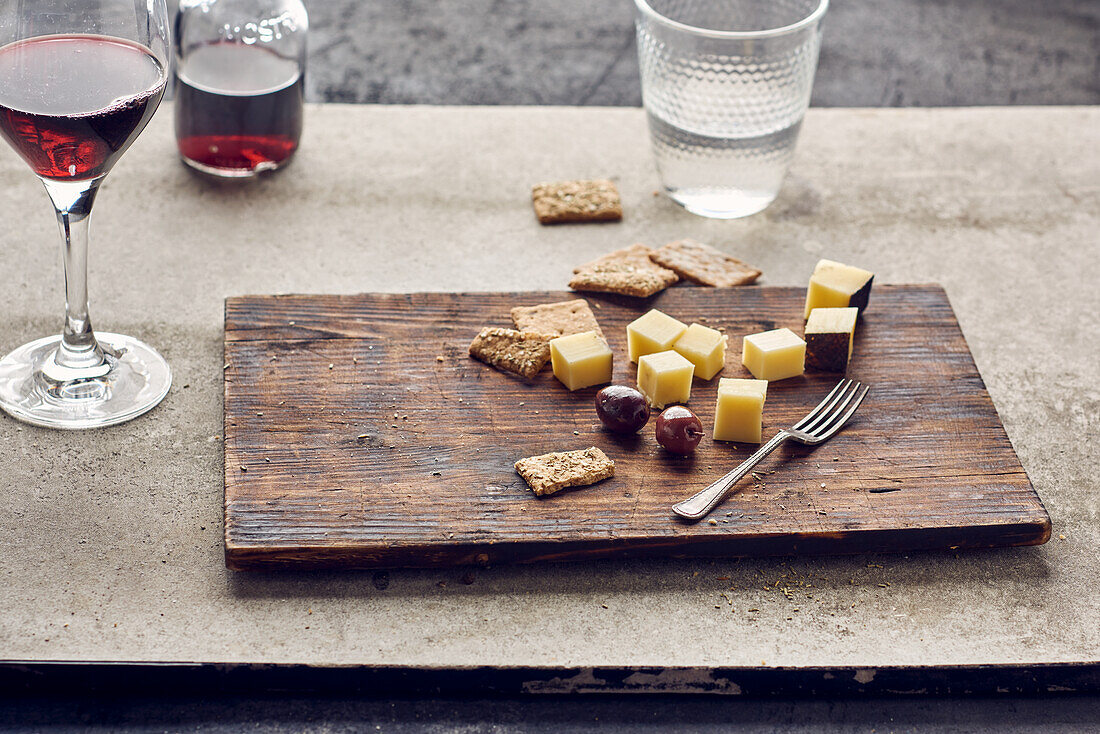 Käsewürfel mit Oliven und Crackern dazu Rotwein