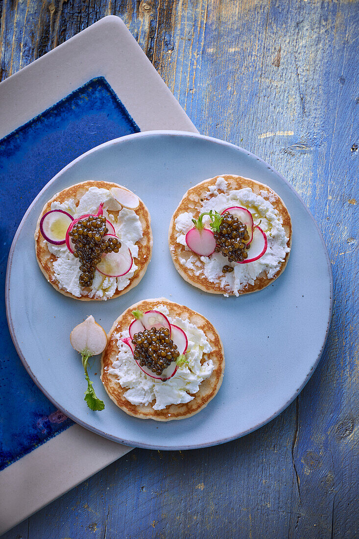 Blinis topped with goat's cream cheese, radishes and caviar