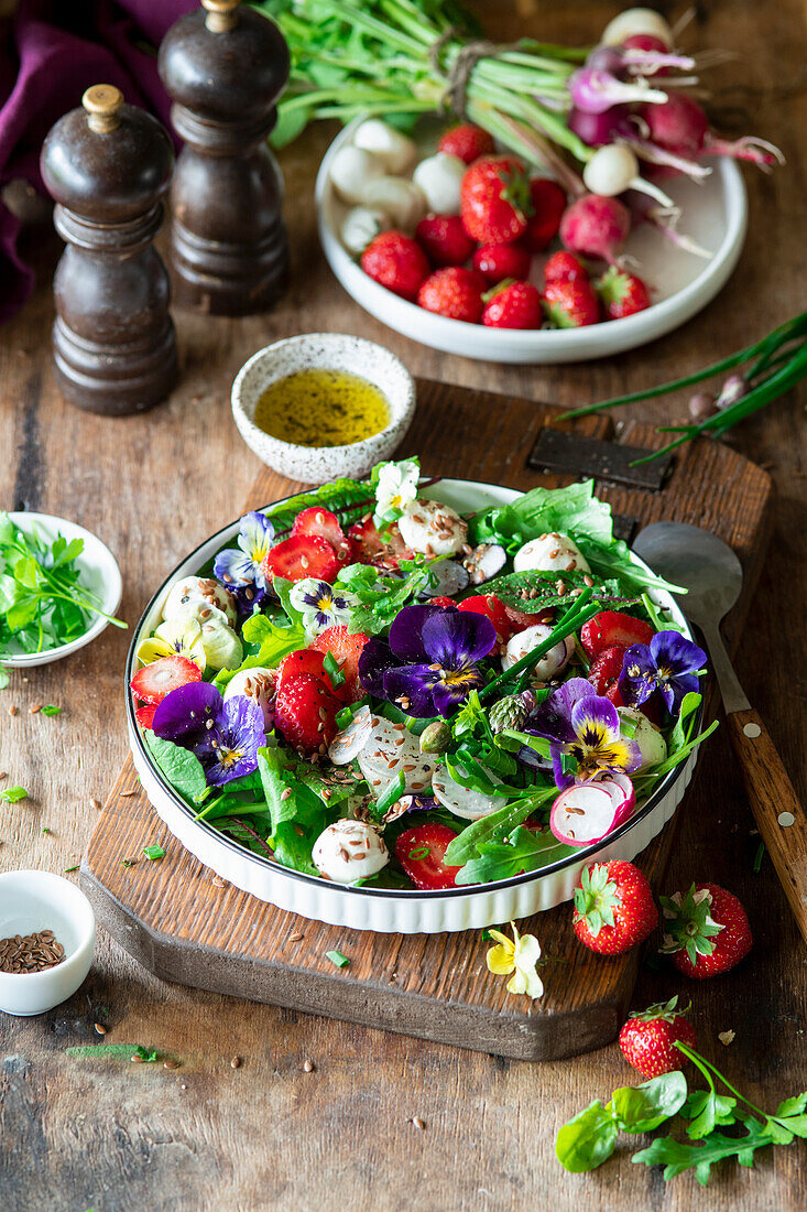 Strawberry salad with mozzarella, edible flowers violets and radishes