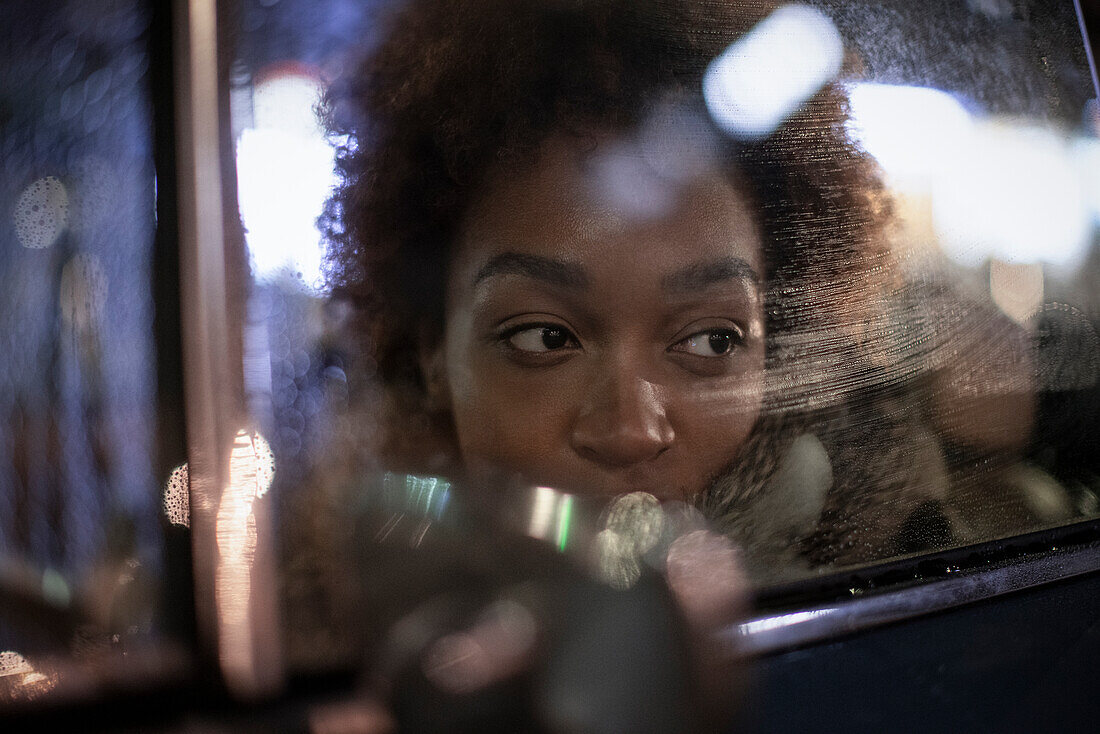 Young woman looking out car window at night