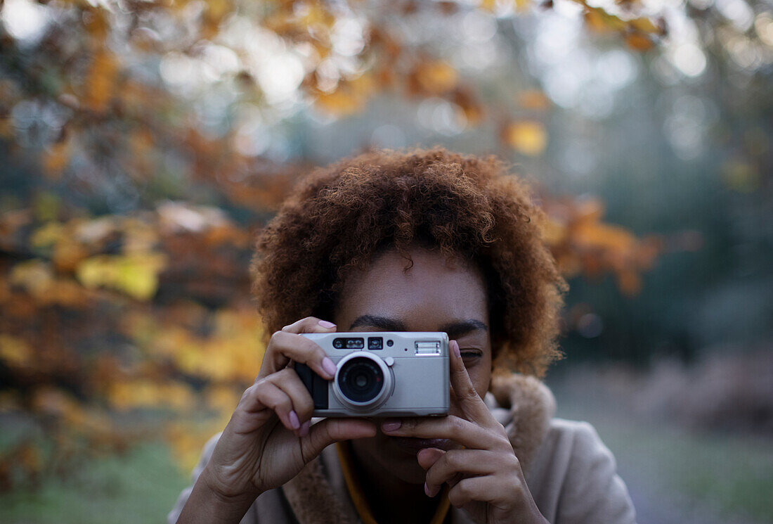 Young woman with digital camera in park