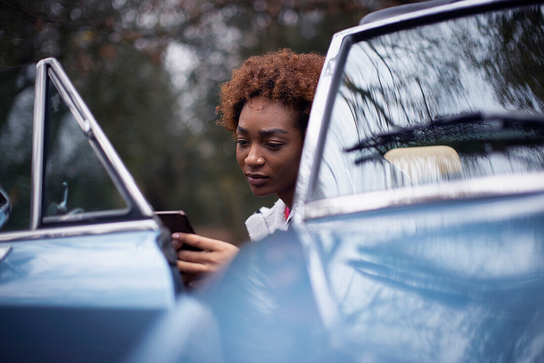 Young woman using smartphone in convertible doorway