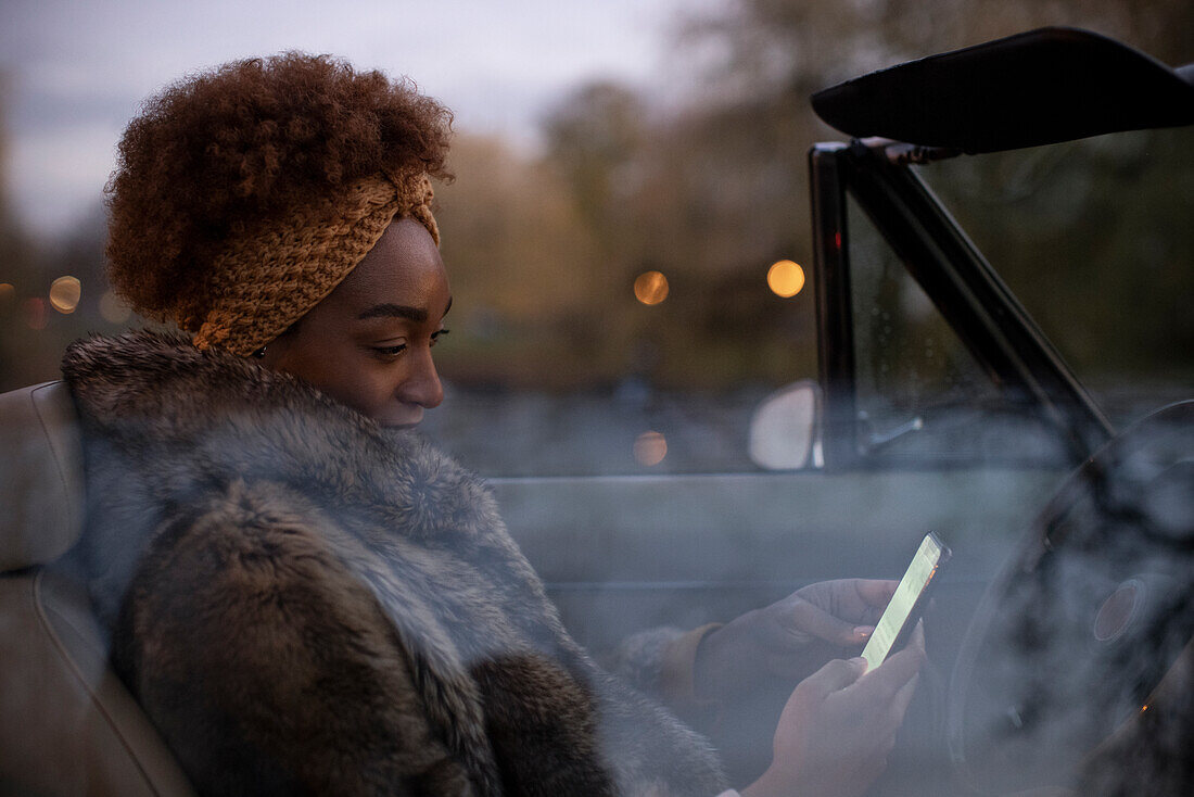 Young woman using smartphone in convertible