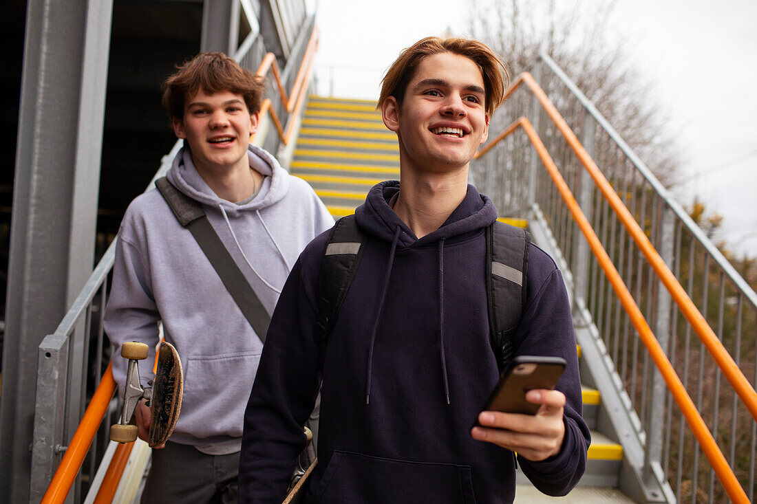 Happy teenage boys with smartphone on urban staircase