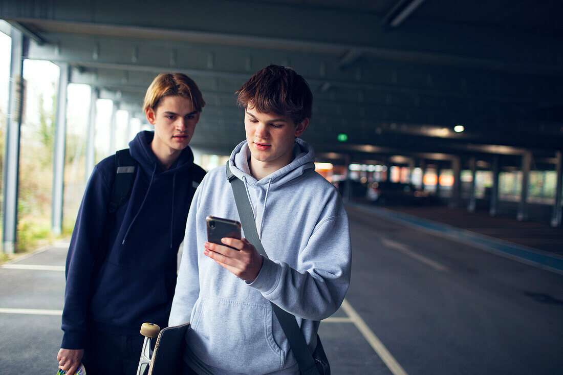 Teenage boys using smartphone in car park