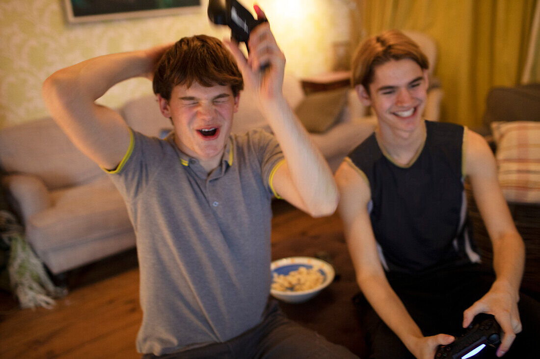 Happy teenage boys playing video game in living room