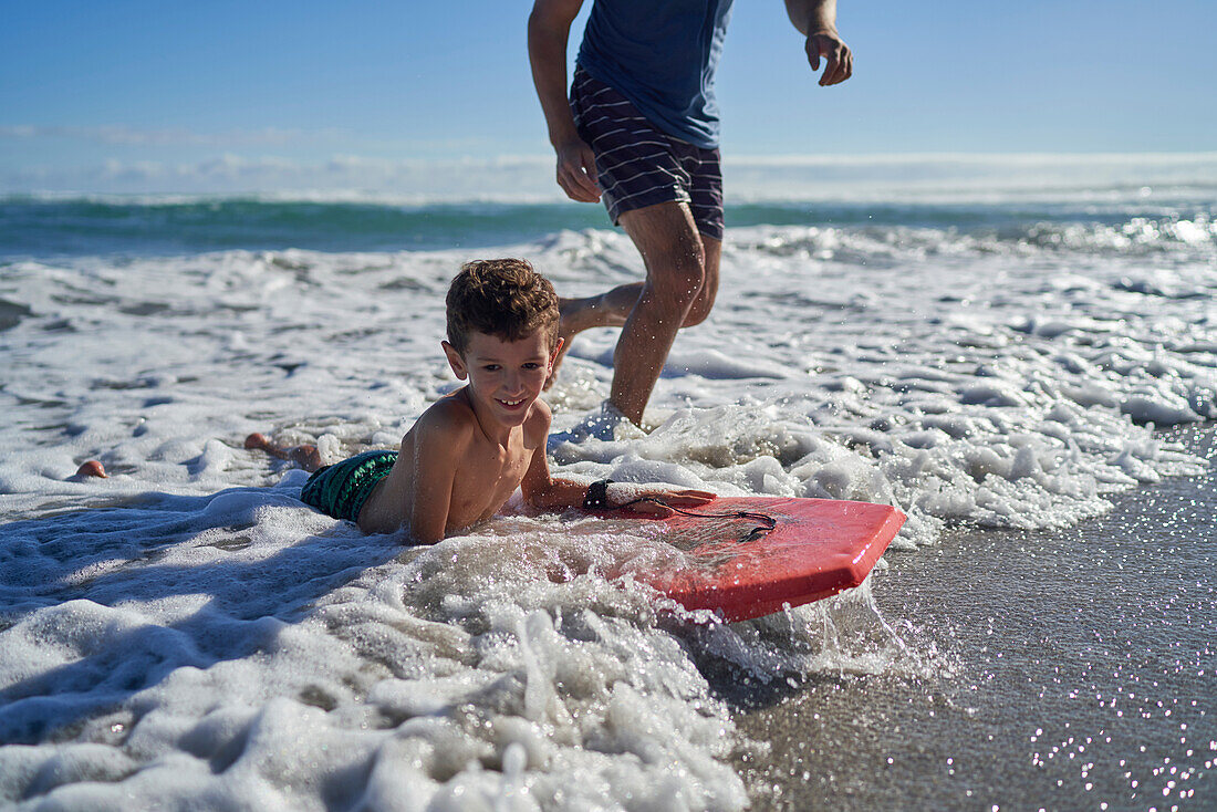 Happy boy body boarding in sunny summer ocean surf