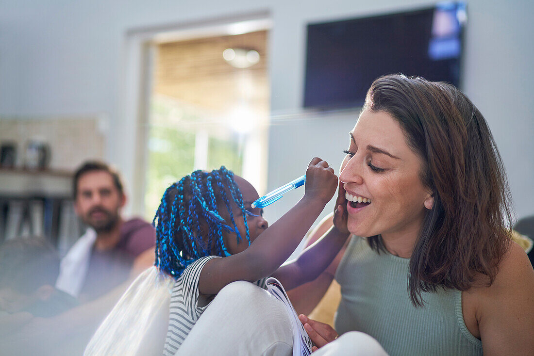 Playful toddler girl with pen writing on mother