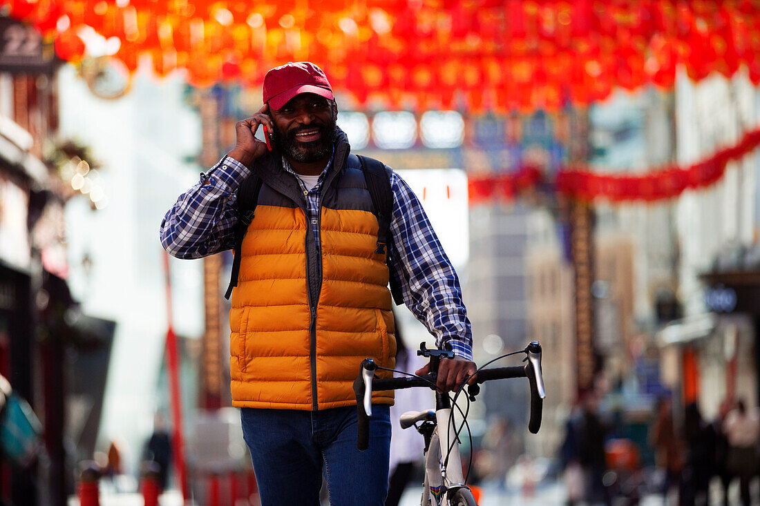 Man with bicycle talking on smartphone in city