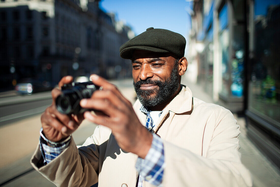 Male tourist with digital camera on sunny urban sidewalk