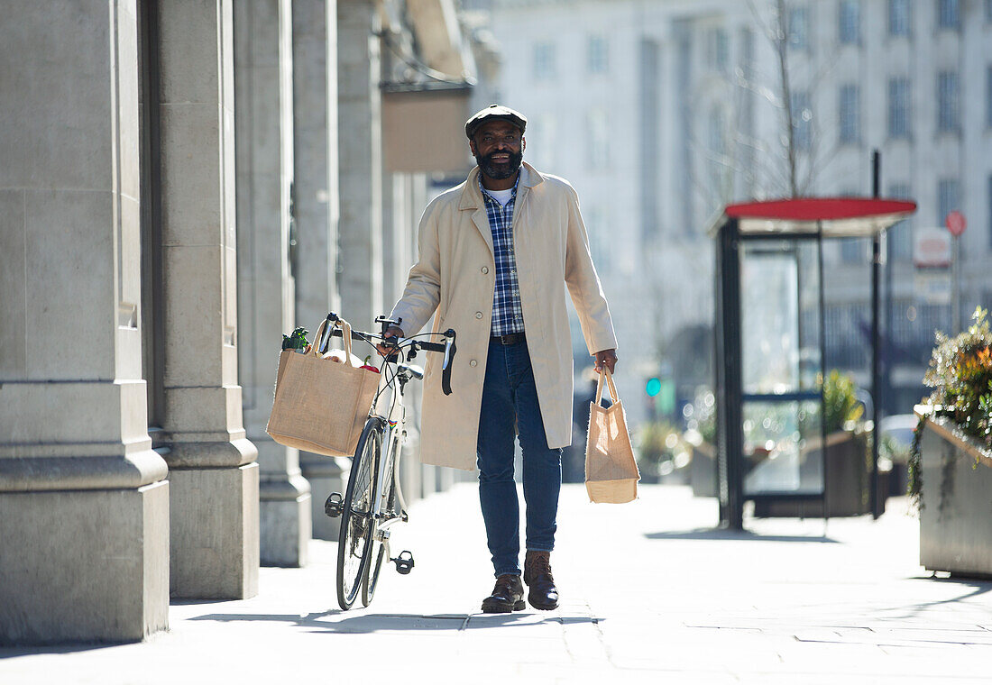 Man with bicycle and groceries walking on city sidewalk